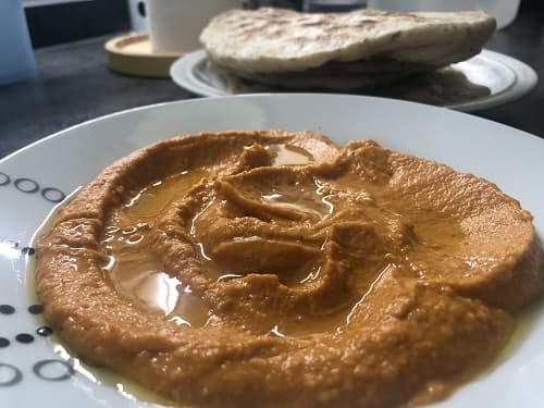 Hummus de pimientos del piquillo emplatado y aderezado con aceite de oliva
