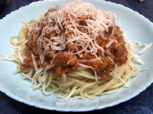 Espaguetis con salsa boloñesa, queso parmesano rallado y oregano