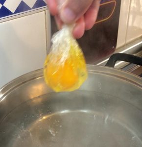 Poniendo huevos en agua hirviendo para hacerlos poche envueltos en film