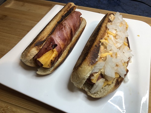 Perritos calientes, salchicha rellena de queso y envuelta en bacón acompañada con salsa burguer y cebolla picada