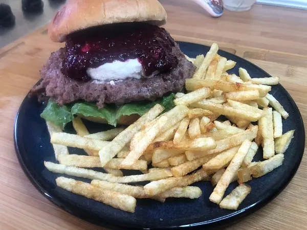 Hamburguesa con lechuga, queso de cabra y salsa de frutos rojos. Acompañada con patatas fritas caseras.