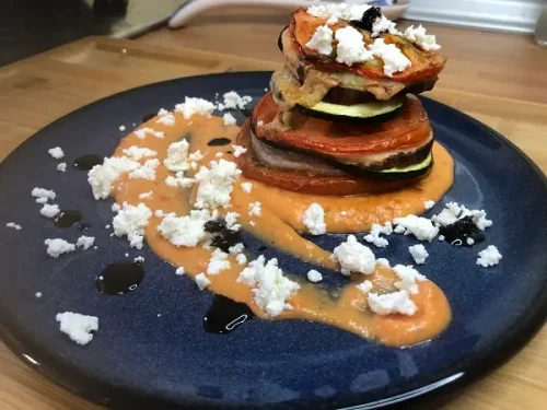Mil hojas de berenjena con verduras, salsa de tomate y requesón.